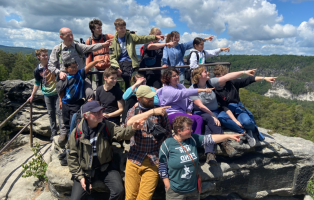 Eine Wandergruppe aus jungen Menschen auf dem Gipfel